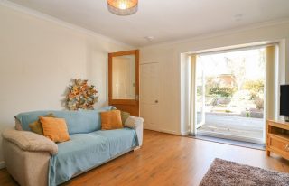 Living area with patio doors leading to garden at Blue Skies Cottage in Auchmithie